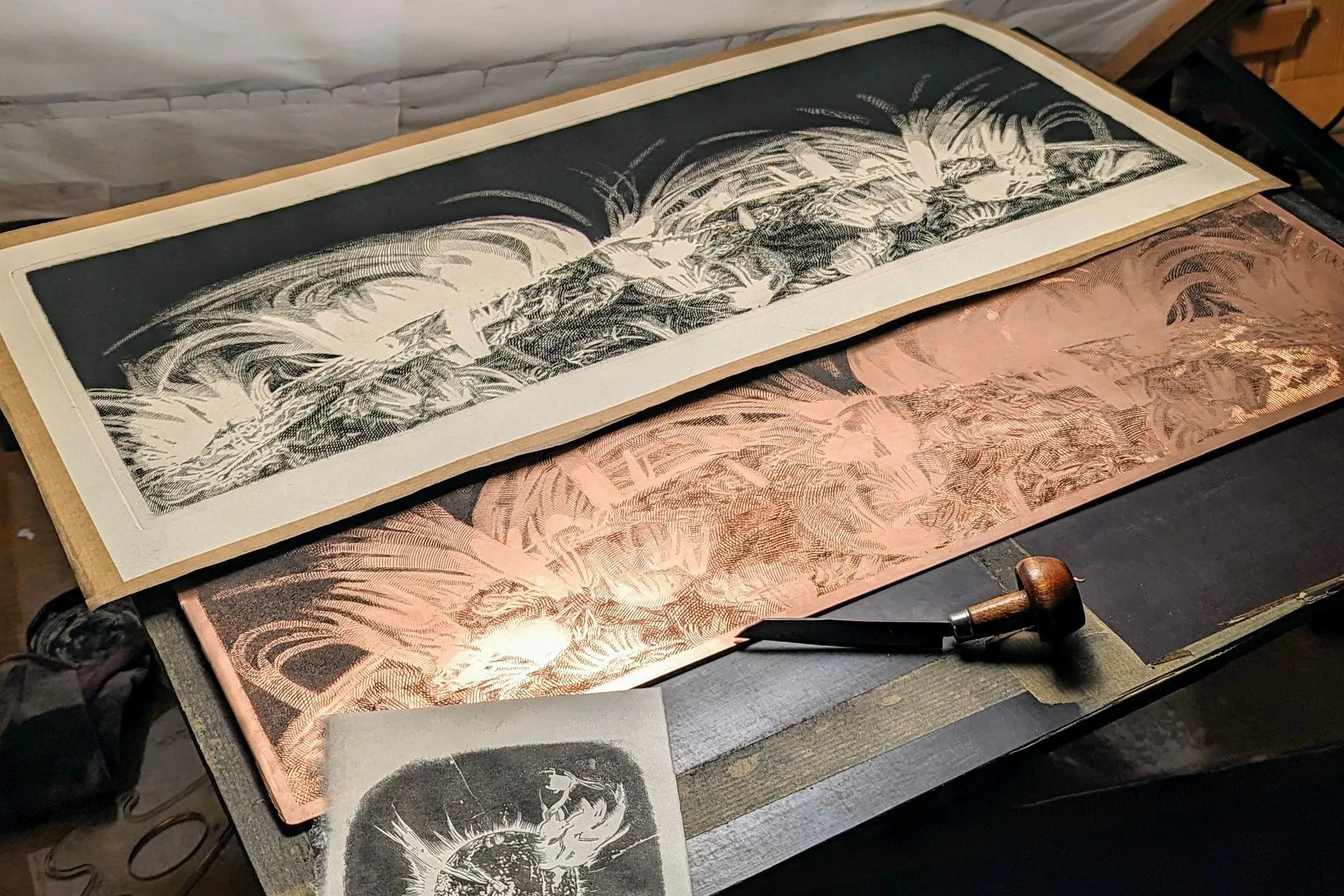 An impression of Sun lying beside its engraved copper plate on a workbench, a burin resting on the copper and a small proof of End in the foreground.