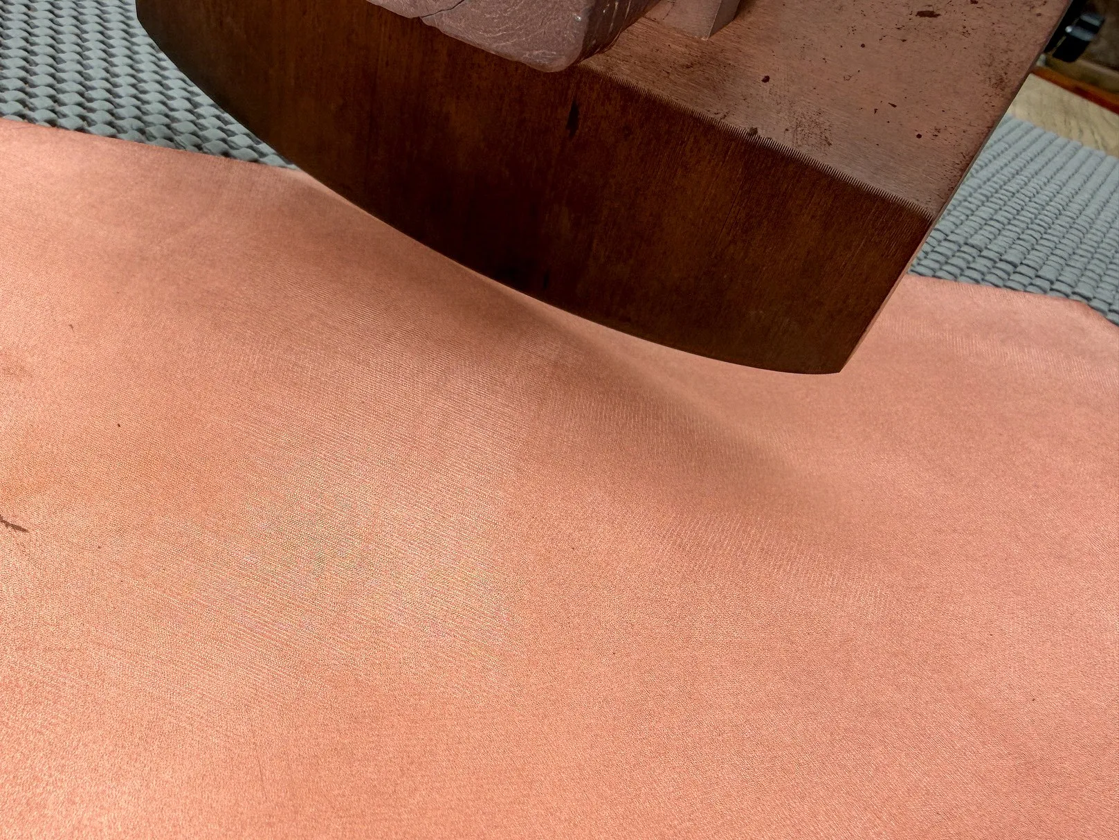 A toothed steel rocker resting on a copper plate. Most of the plate surface has been worked to a fine even texture; a section towards the edge is still bare polished copper.