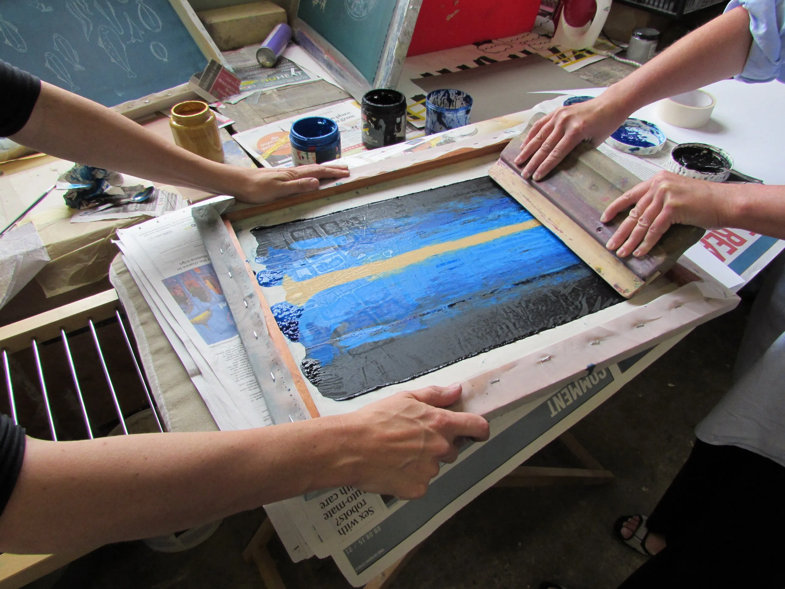 A studio photograph of screen printing — ink pushed through a fine-mesh screen with a squeegee.